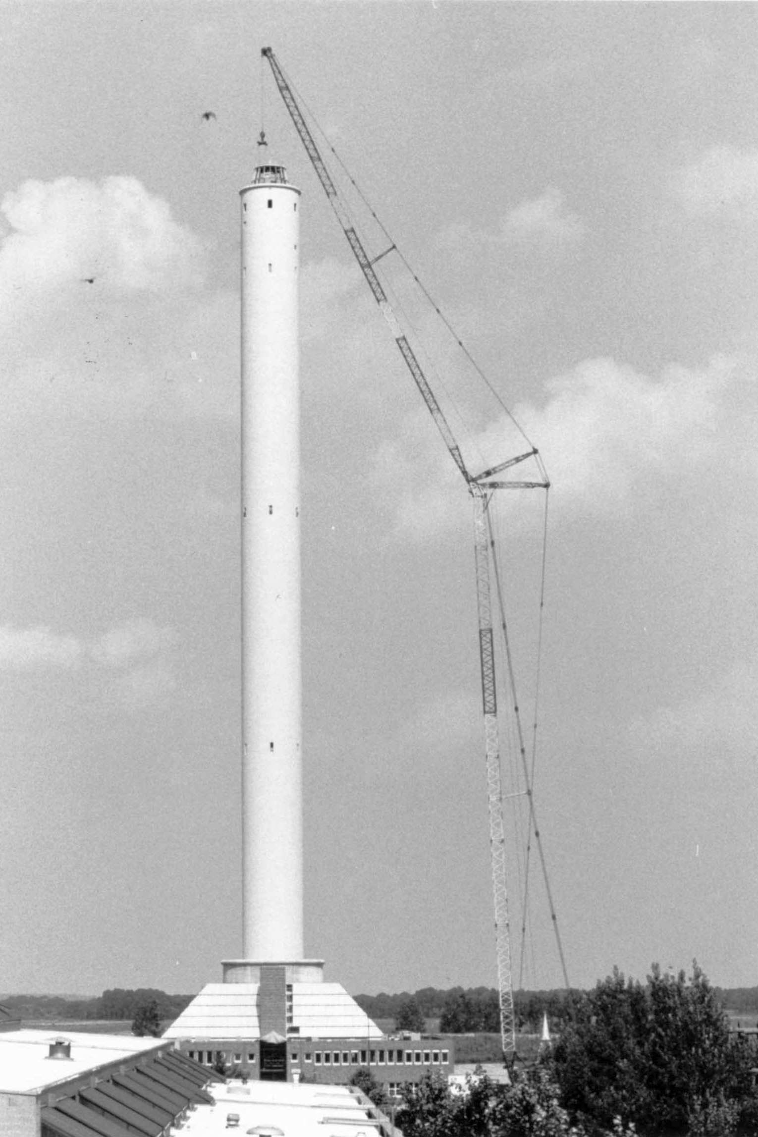 Vier Fotos zeigen die schrittweise Montage der kegelförmigen Spitze auf dem Fallturm im August 1989.