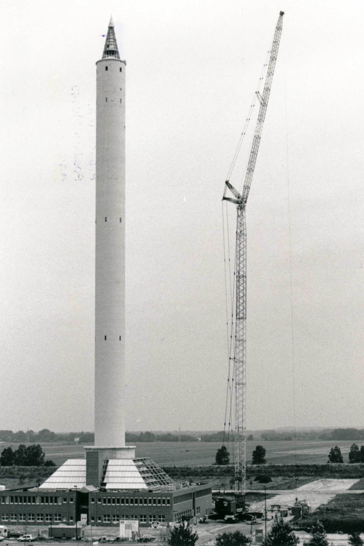 Vier Fotos zeigen die schrittweise Montage der kegelförmigen Spitze auf dem Fallturm im August 1989.