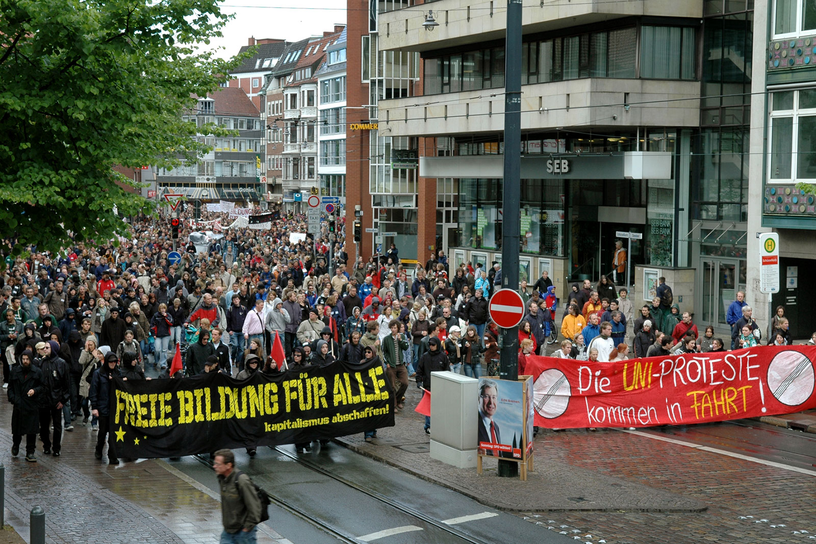 Ein Protestzug von mehreren Hundert Menschen zieht am Bremer Schüsselkorb vorbei. Mehrere Protestierende halten Plakate und Spruchbänder.