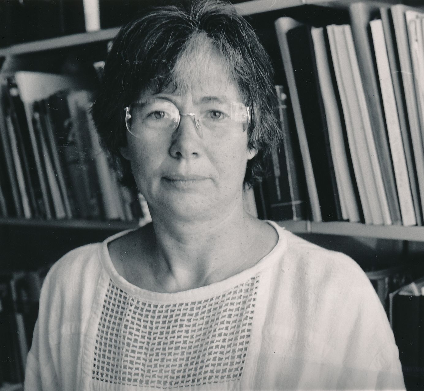 Hannelore Schwedes im Jahre 1989 vor einem Bücherregal. Sie trägt eine randlose Brille und eine helle Bluse und blickt direkt in die Kamera.