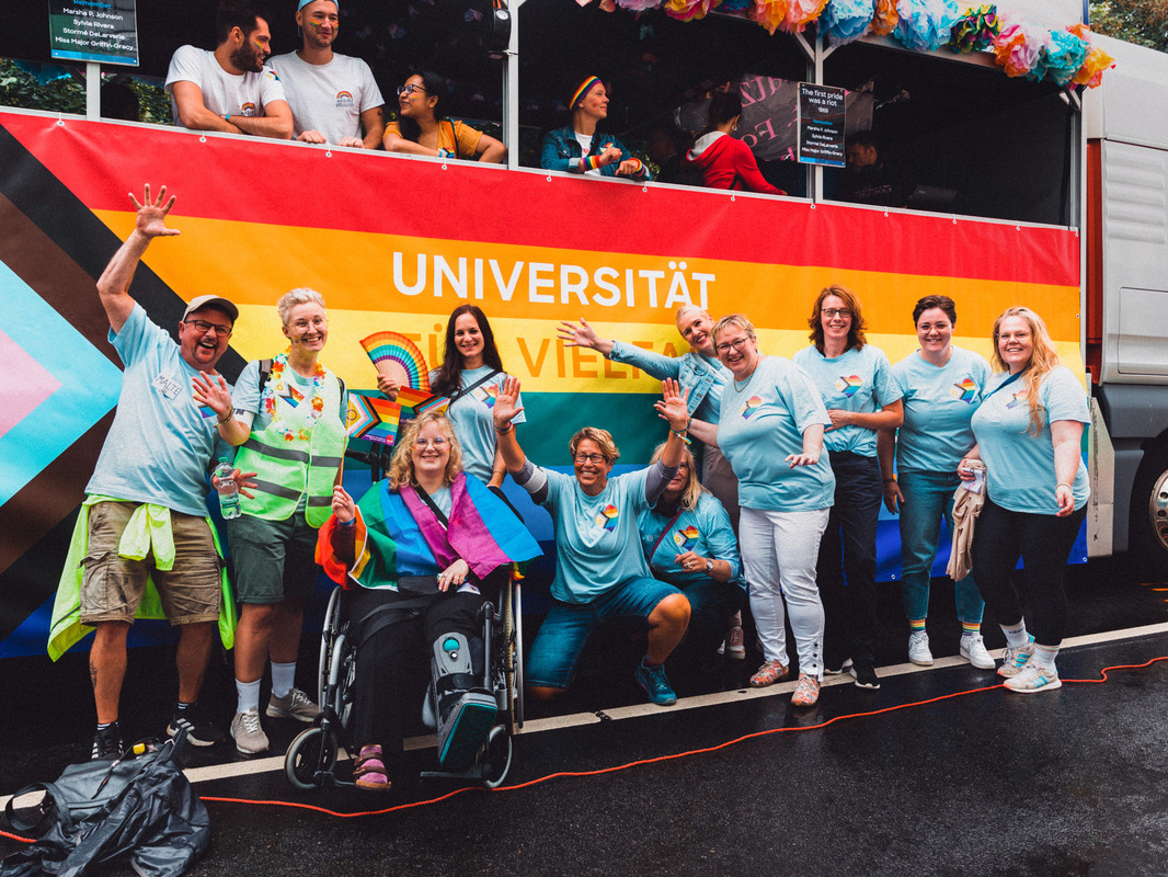 Uni-Angehörige posieren vor einem Uni-Wagen beim CSD 2023 in Bremen