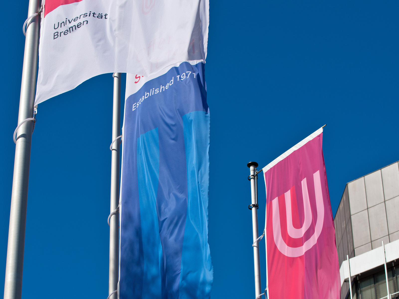 Zwei Flaggen wehen vor dem  MZH-Gebäude der Universität Bremen