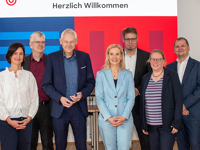 Sieben Personen posieren vor einem Banner mit Logo der Universität Bremen.